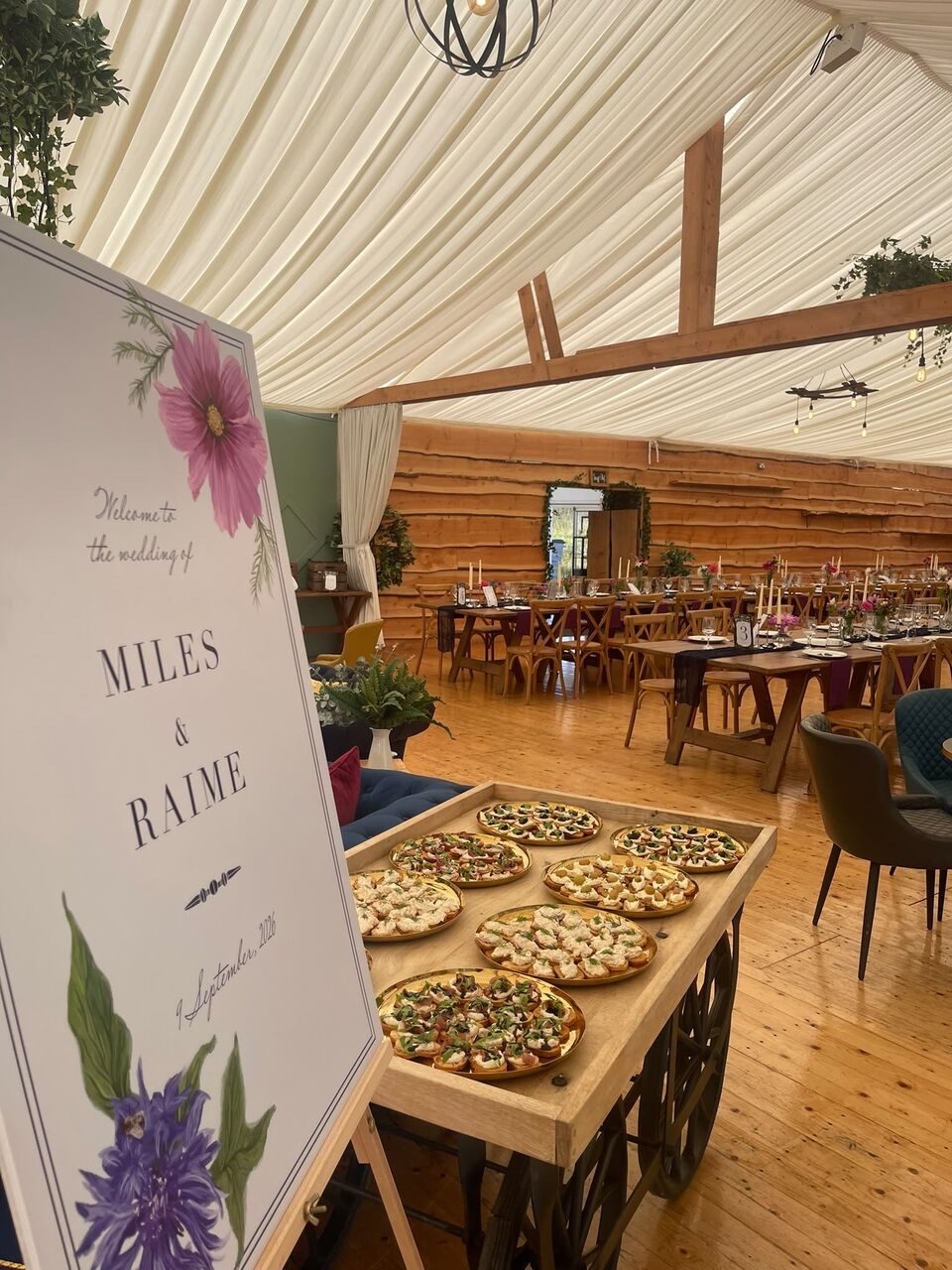 Wedding welcome sign beside a trolley of canapés in a marquee