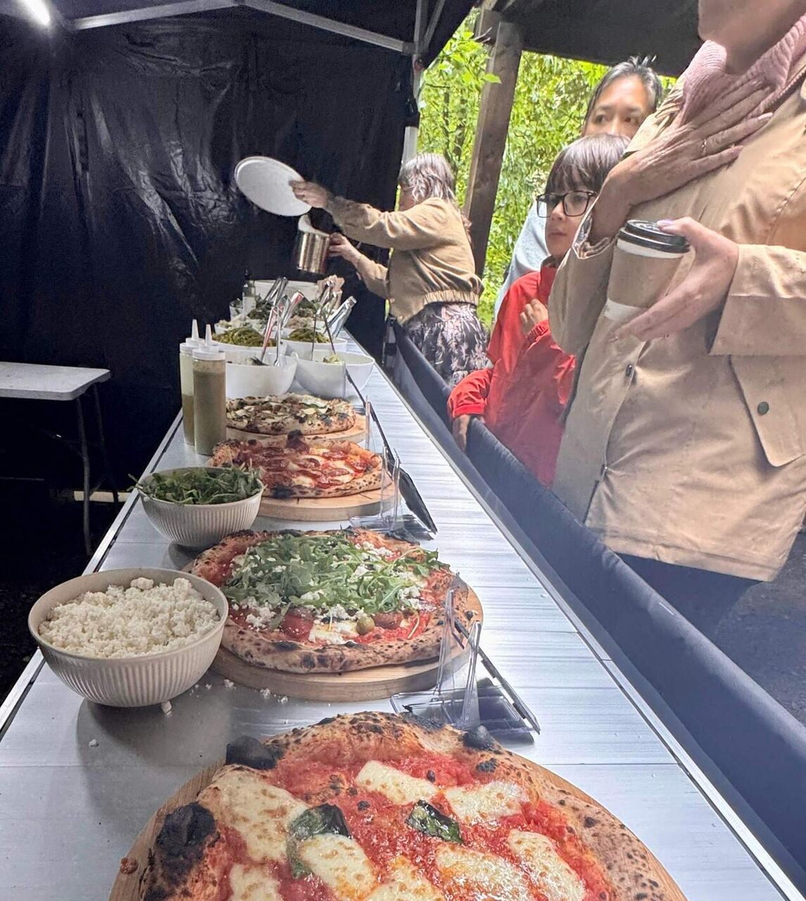 Guests helping themselves to pizza and sides at the service counter
