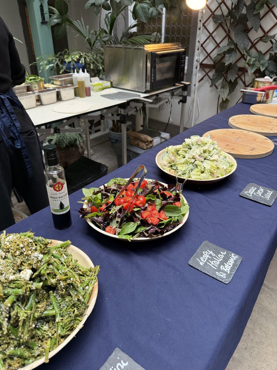 Indoor pizza pop-up with salads laid out on a navy-dressed table