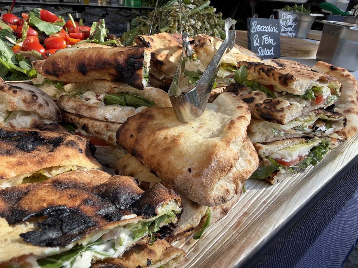 Freshly baked sub sandwiches with mozzarella, tomato and rocket on a Scottish Pizza Co serving board