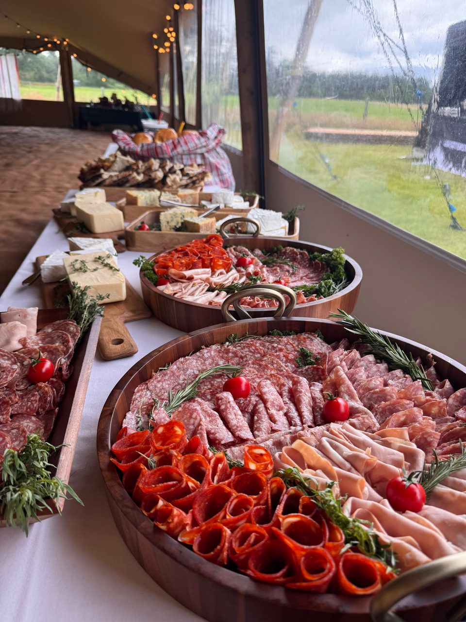 Charcuterie grazing table with cured meats and roasted peppers in a wedding marquee